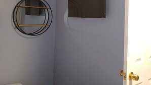 A room with a bed, a wall-mounted TV, a circular mirror, and a door. - Compact Studio Lovely, Privacy Affordable safe And Quite #3 (Phoenix)
