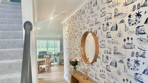 Una escalera conduce a una sala de estar con un mueble consola de madera y un espejo.