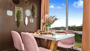 Un comedor con una mesa blanca, sillas rosas y un jarrón de flores.