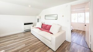 Ein weißes Sofa mit roter Decke, eine weiße Wand und Holzboden.