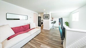 Ein modernes Wohnzimmer mit einem weißen Sofa, einer roten Decke und einem an der Wand befestigten Flachbildfernseher.