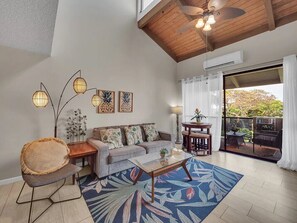 A spacious living room with a sofa, coffee table, and decorative lamps. - Kona Retreat • Ocean View, Pool & Walk to Beach (Kailua-Kona)