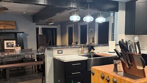 A modern kitchen with a central island, black cabinetry, and pendant lighting. - Newly renovated Ashton Farmhouse on Cave  Falls HWY. Near Yellowstone Nat. Park (Ashton)
