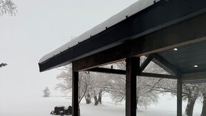 A covered outdoor area with a snow-covered roof and a metal bench. - Newly renovated Ashton Farmhouse on Cave  Falls HWY. Near Yellowstone Nat. Park (Ashton)