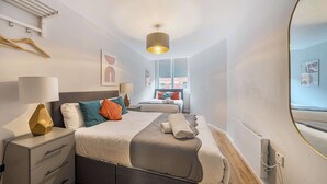 Una camera d'albergo moderna con un letto, comodini, una lampada e vista all'esterno.
