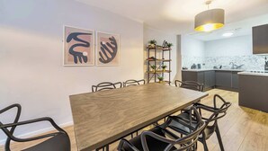 Una cucina moderna con un tavolo da pranzo e sedie in legno, una lampada a sospensione e un'isola integrata con lavello.