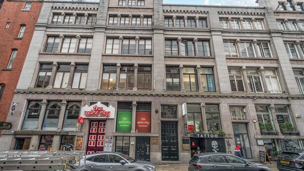 Un edificio a più piani con diversi negozi al piano terra, tra cui un centro massaggi e spa, un ristorante e un negozio di tatuaggi.