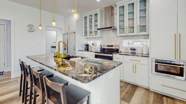 A modern kitchen with white cabinets, a marble island, and gold fixtures. - Modern Living in Texas! Home 2 Blocks to Lake LBJ (Granite Shoals)