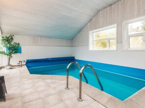 An indoor swimming pool with a blue interior, metal pool ladders, and a potted plant. - 5 Star Holiday Home in Gilleleje (Gilleleje)