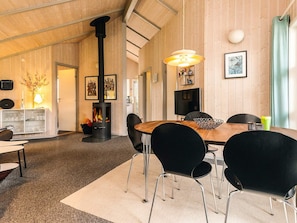 A cozy room with a wooden interior, a dining table with chairs, a fireplace, and a television. - 5 Star Holiday Home in Gilleleje (Gilleleje)
