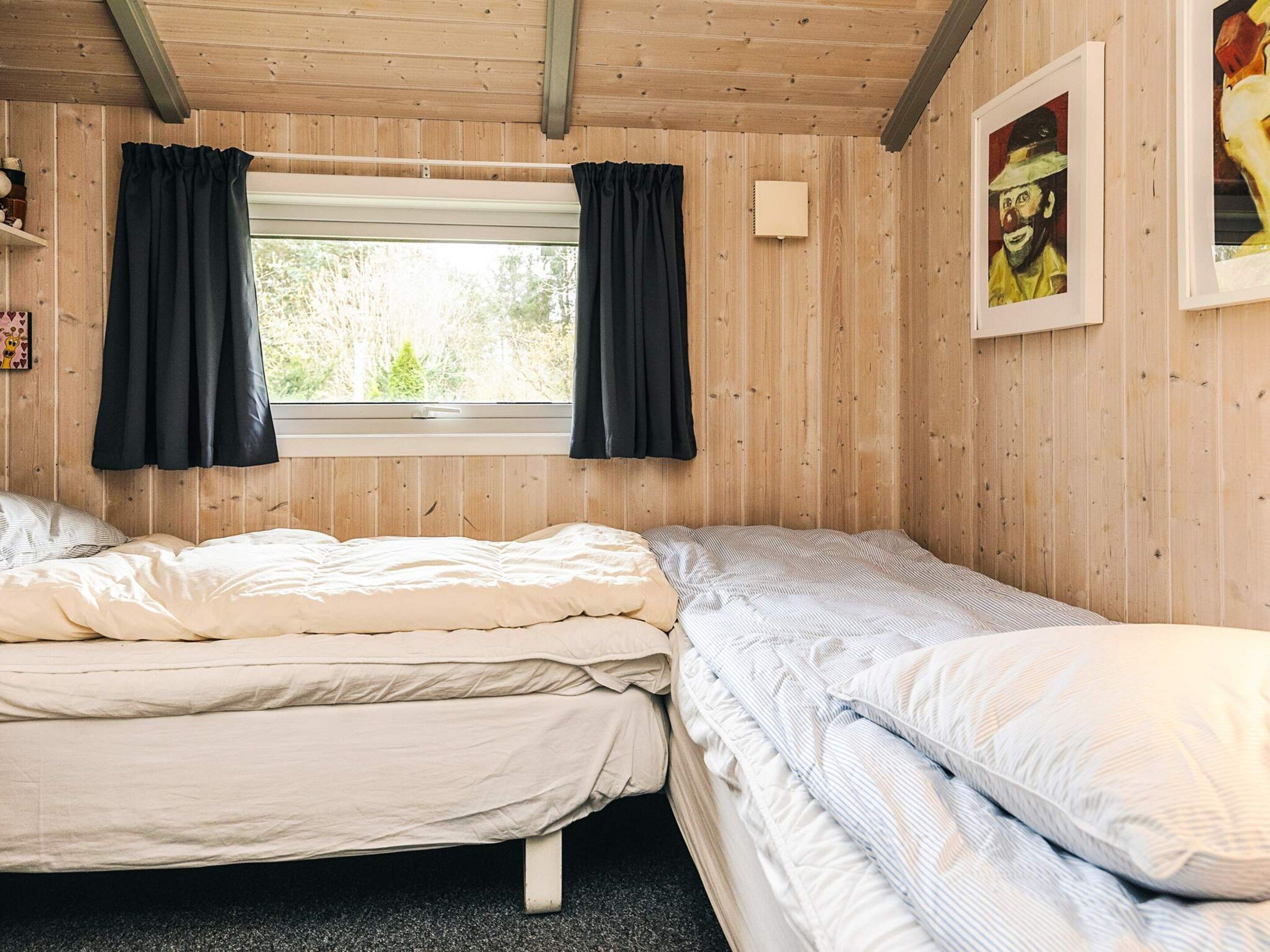 Habitació amb dos llits, una finestra amb cortines i un quadre al mur.