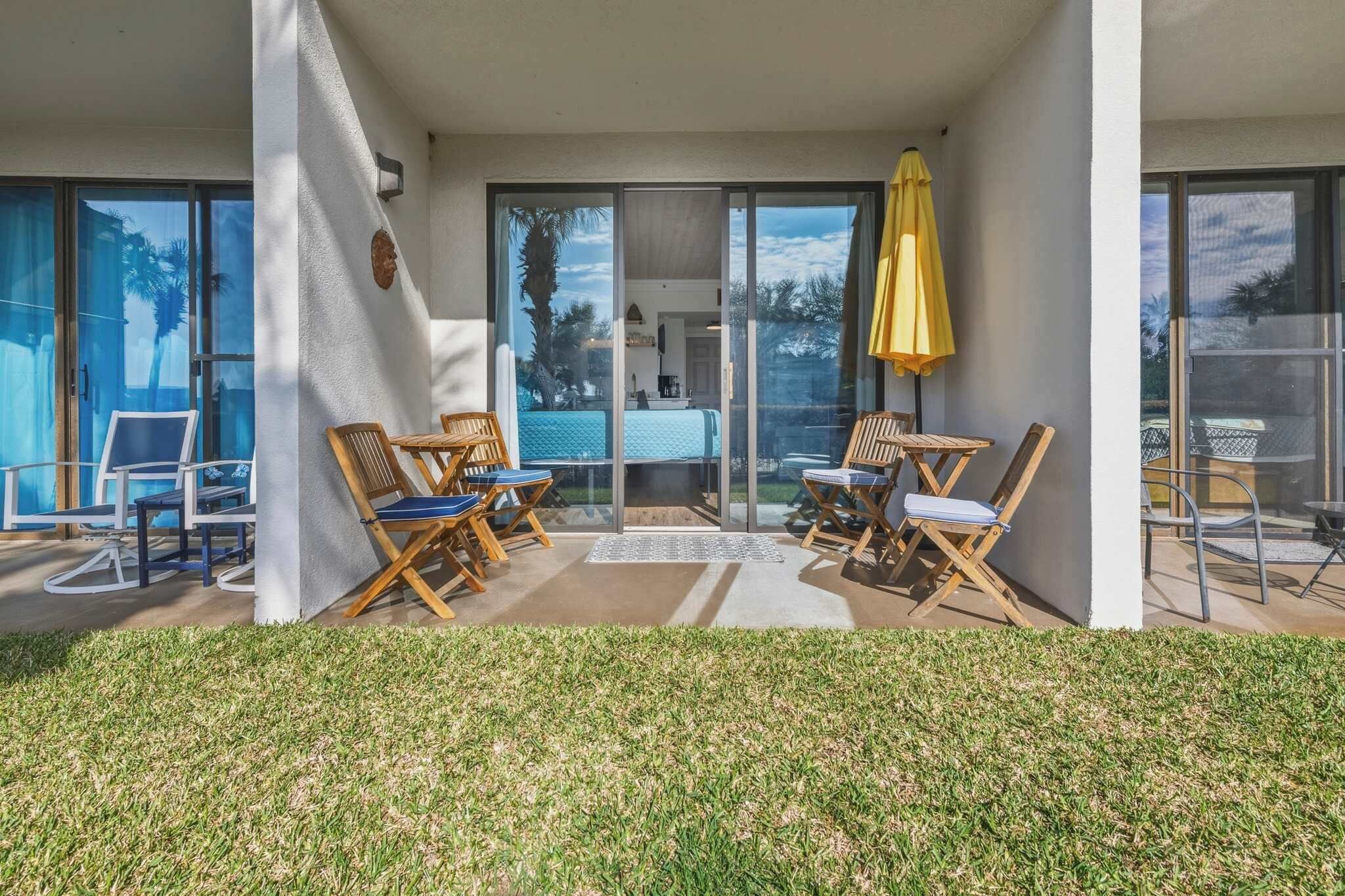 A modern hotel room with a balcony, large windows, and a yellow umbrella.