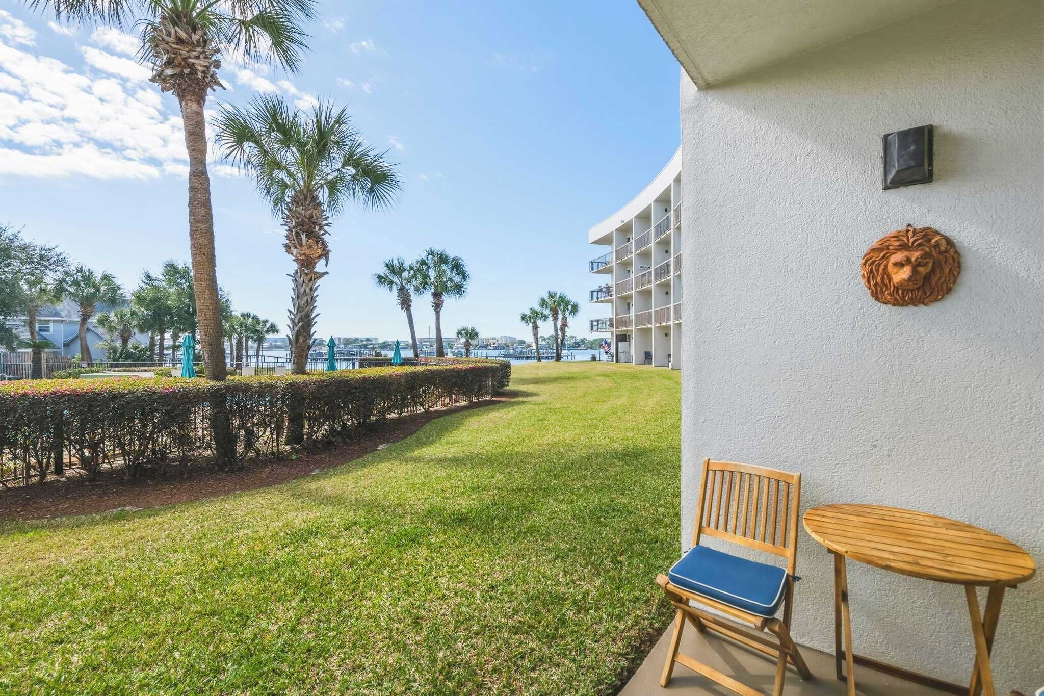 A balcony with a view of the sea, a chair, a small table, and a decorative lion head.