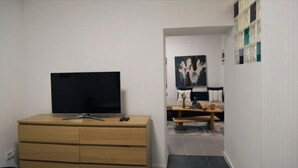 Un salon avec un téléviseur posé sur un meuble en bois, un canapé et une table basse.