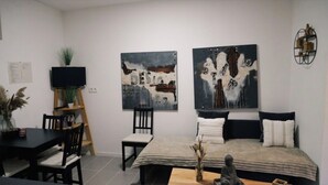 Un salon moderne avec un lit, un téléviseur et des œuvres d’art accrochées aux murs.