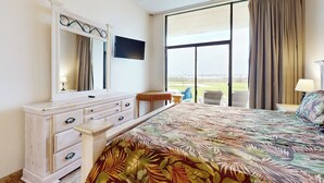 A hotel room with a large bed, a dresser, a television, and a view of the outdoors. - Ground-Floor Gulf-View 3BR: Suntide III - Unit 106 (South Padre Island)