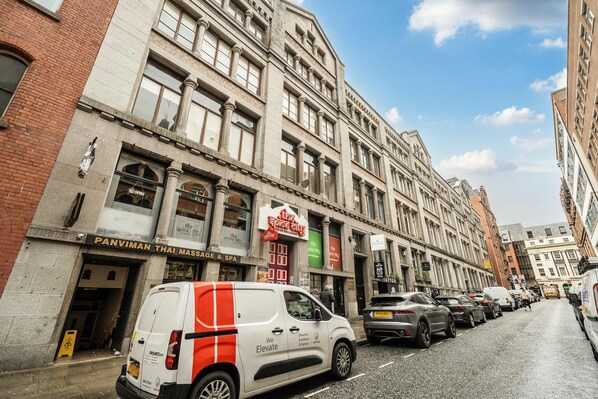 A street view with a white van parked in front of a building with multiple shops, including a Thai massage and spa. - Host Stay Apartment 6 Stanley Street (Liverpool)