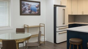 Una cocina moderna con armarios blancos, un refrigerador integrado y una pequeña isla con taburetes.