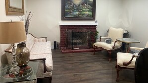 Una sala de estar acogedora con chimenea, asientos cómodos y un cuadro grande colgado arriba.