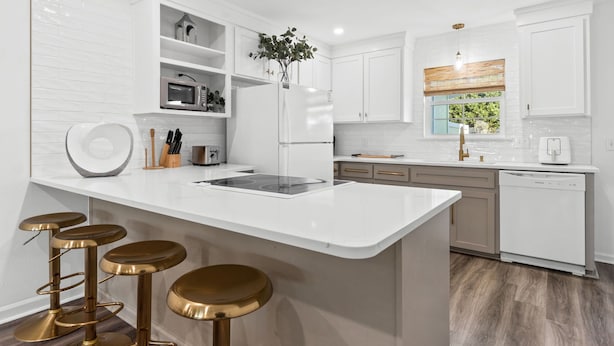 A modern kitchen with white cabinetry, a central island with stools, and a view of the outdoors. - Townhouse Directly Across from Gulf- 2BR/2.5Ba (Panama City Beach)