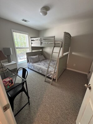 Ein Schlafzimmer mit Etagenbetten, einem Schreibtisch und einem Stuhl.