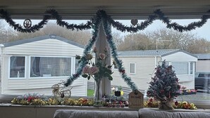 A view from inside a covered porch with a Christmas tree, decorations, and a sign that reads "HOME & Friends". - Willerby Seasons: 3BR Caravan (Morecambe)
