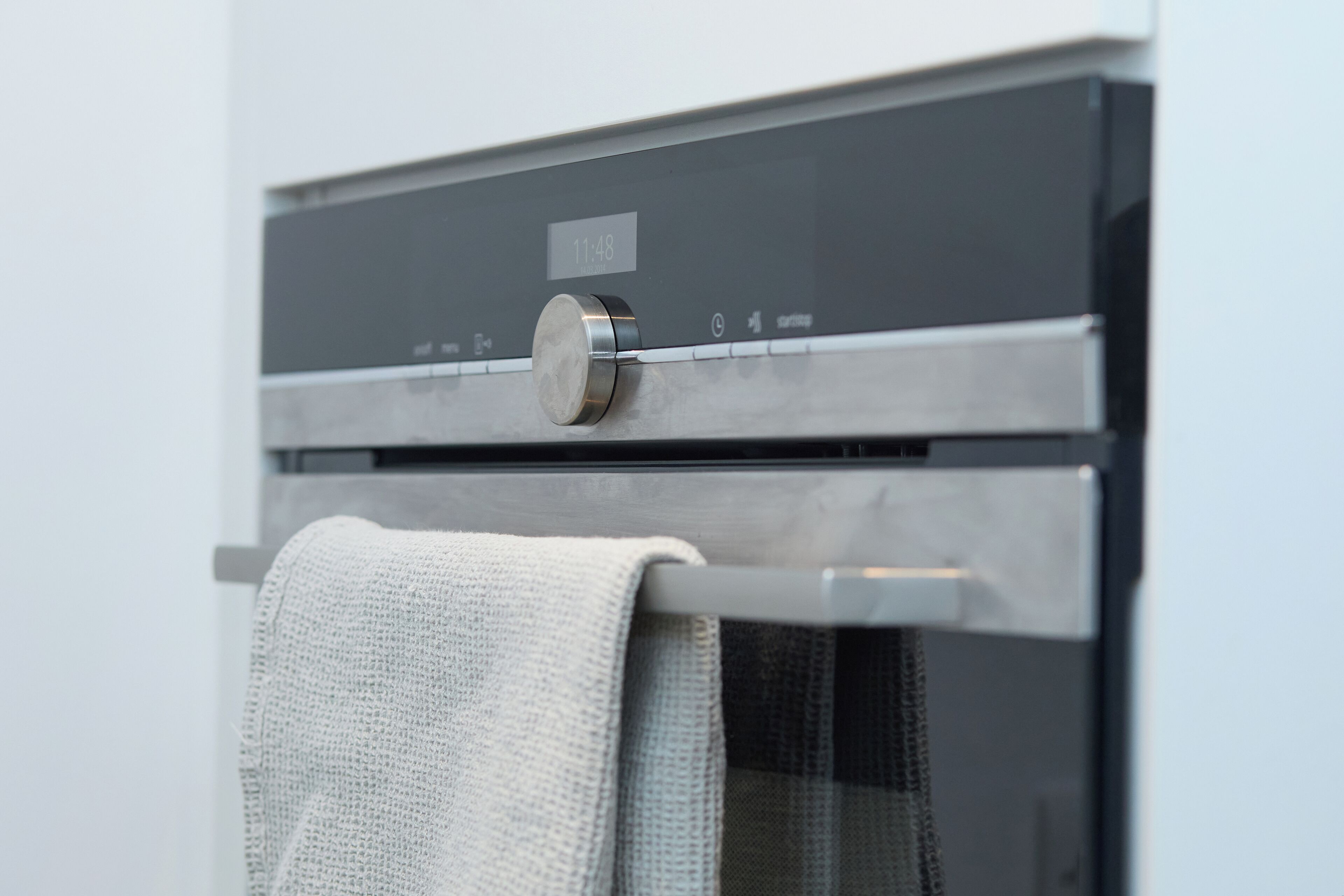 A modern kitchen with a stainless steel oven and a visible timer set to 11:48.