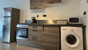 Eine moderne Küche mit einem Edelstahl-Kühlschrank, Backofen, Mikrowelle und Waschmaschine.