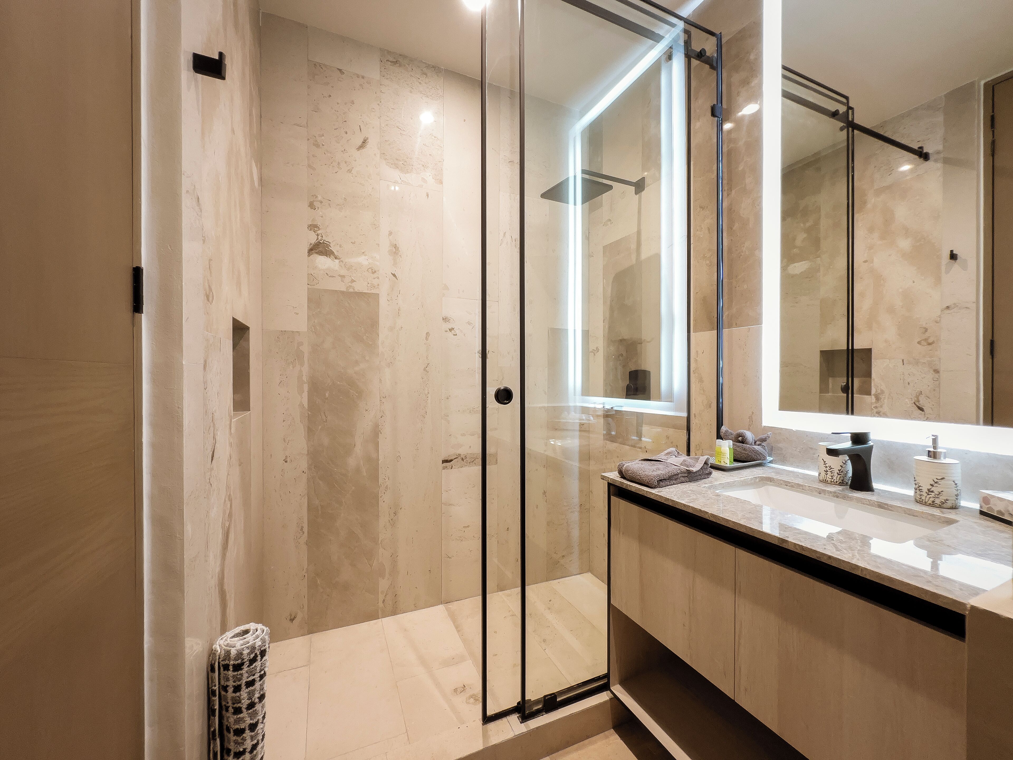 Une salle de bain moderne avec une douche à parois de verre, un grand miroir et un plan de toilette en marbre.