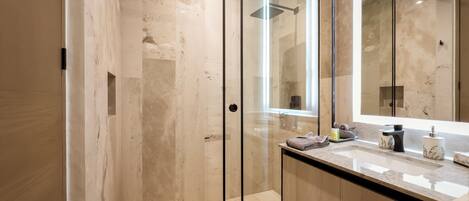 Une salle de bain moderne avec une douche à parois de verre, un grand miroir et un plan de toilette en marbre.