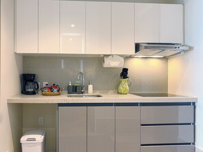 A modern kitchen with white cabinets, a coffee maker, a sink, and a trash bin. - Casa la Aurora (Puerto Morelos)