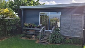 A modern house with a wooden deck, a staircase, and a variety of potted plants.