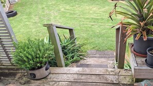 A wooden staircase leading to a grassy yard with potted plants.
