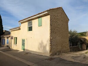 Un edificio de dos pisos con fachada color crema, techo de tejas y puerta verde.