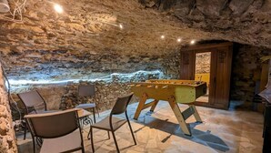 Un espace intérieur chaleureux avec un baby-foot, des murs en pierre et une petite table de billard.