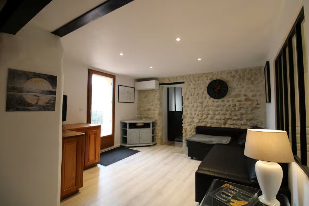A living room with a stone wall, a sofa, a lamp, and a wooden cabinet.