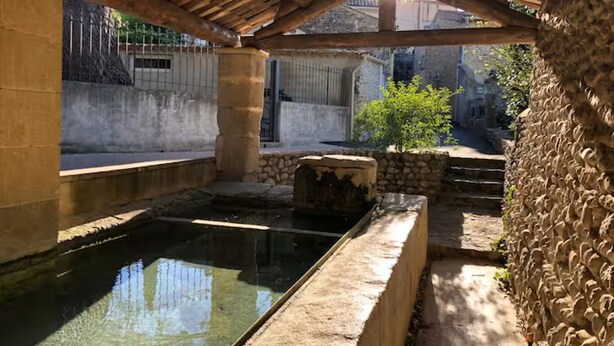 Une cour avec une piscine, des murs en pierre et une pergola en bois.