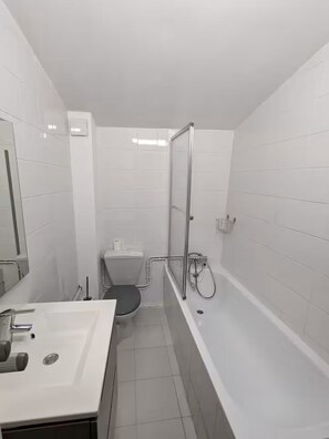 Un baño con lavamanos, inodoro y bañera blancos.