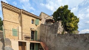 Un bâtiment à deux étages, doté d’une façade en pierre, d’un petit balcon et d’une piscine.