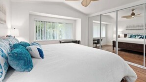 A modern bedroom with a large bed, a ceiling fan, and a sliding glass door leading to another room. - Luxury Oasis Resort Villa (Kapolei)