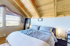 A bedroom with a wooden ceiling, a bed with grey bedding, a bedside table with a lamp, and a window with blinds. - Views, Deck & Games Galore: Brian Head Home (Brian Head)