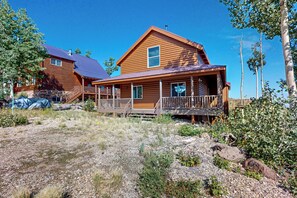 A wooden cabin with a porch, a stone foundation, and a clear blue sky. - Views, Deck & Games Galore: Brian Head Home (Brian Head)