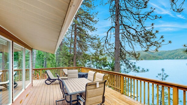 A wooden deck with a table and chairs, overlooking a lake and forest. - Dock, Deer Lake Access! Fishermen's Paradise (Loon Lake)