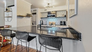 A modern kitchen with a central island, bar stools, a hanging light fixture, and a geometric backsplash. - ‘Lakeside Getaway’ w/ Patio on Lady Bird Lake (Austin)