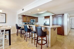 A modern kitchen with a central island, bar stools, and built-in appliances. - 3BR Gulf-View Resort Condo: Suntide III - Unit 605 (South Padre Island)