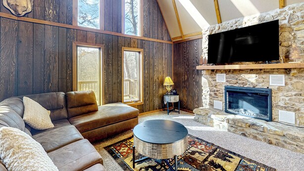 Ein gemütliches Wohnzimmer mit Kamin aus Stein, Ledersofa und großem Flachbildfernseher.
