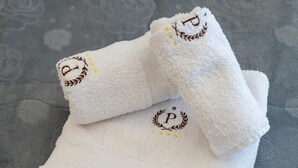 Toalla blanca con iniciales bordadas y un logo de laurel.