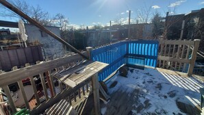 Eine Holzterrasse mit einem blauen Zaun, einem Metallgeländer und blauem Himmel.