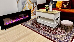 Un saló modern amb televisió de pantalla plana, una taula baixa decorativa, un sofà vermell amb coixinets estampats i una catifa amb dibuixos.