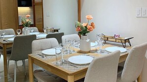 En matplats med ett träbord dukat för fyra personer, vita stolar och en vas med blommor.